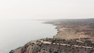 Kıbrıs havadan görünüyor. Bir İHA denizin ve dalgalarının Akdeniz 'deki kayalık bir kıyıya çarptığı kıyı şeridinde uçuyor. Güzel doğa manzarası video arka planı. Yüksek kalite 4k 