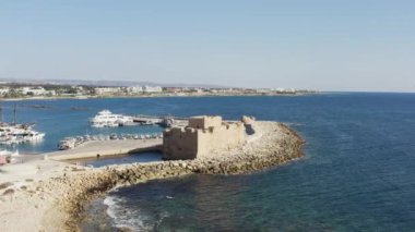 Akdeniz kıyılarında dalgaların çarptığı kıyı şeridine karşı duran eski tarihi kalenin üzerinde uçan insansız hava aracı. Paphos Kıbrıs havadan görüşü. Yüksek kalite 4k görüntü
