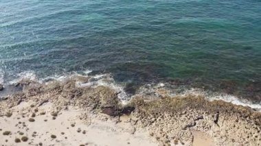 Drone flying over the rocky shore of the island in the Mediterranean Sea where the waves crash against rocks and cliffs. Aerial view coastline Cyprus. High quality 4k footage