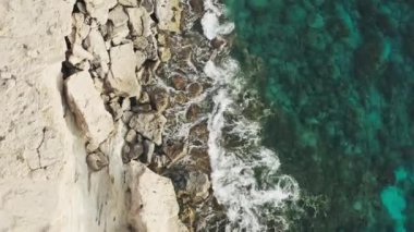 Kıyı şeridinin havadan görüntüsü. Okyanus dalgaları, deniz kayalık kıyılara çarpıyor. Akdeniz 'in mavi suları kayalara çarpıyor. güzel manzara video arkaplanı