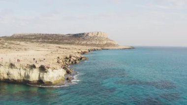 Akdeniz 'in dalgalarını kıran kayalıklara karşı denizin kayalık kıyı manzarası dağın arka planının olduğu güzel bir manzara. Peyzaj video arkaplanı. 