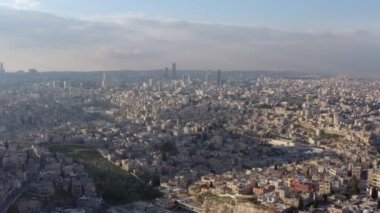 Arap dünyasındaki kentsel manzaranın insansız hava aracı videosu. Gün batımında yolları ve caddeleri olan güzel mahallelerdeki dağlarda evler. Hava manzaralı Amman Jordan. Yüksek kalite 4k görüntü