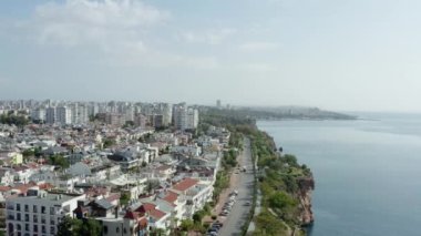 Akdeniz kıyılarının deniz dalgaları tarafından yıkanan kayalık bir şehir kıyısı ve üzerinde eski şehrin evleri ve caddeleri olan insansız hava aracı videosu. Antalya Türkiye 'nin havadan görüşü. Yüksek kalite 4k görüntü
