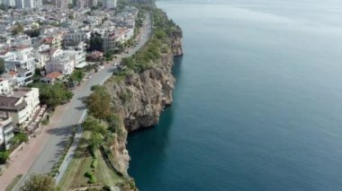 Akdeniz kıyılarının deniz dalgaları tarafından yıkanan kayalık bir şehir kıyısı ve üzerinde eski şehrin evleri ve caddeleri olan insansız hava aracı videosu. Antalya Türkiye 'nin havadan görüşü. Yüksek kalite 4k görüntü