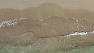 İnsansız hava aracı deniz manzarası. Deniz dalgaları güzel bir manzarada beyaz kumlu plaja çarpar. İnsanlar olmadan doğanın arka plan çerçevesi. Yüksek kalite 4k görüntü