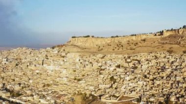 Drone video of a cityscape in a historic city on a rock in Misopotaya. Ancient houses and streets with Middle Eastern architecture. Aerial view Mardin Turkey. High quality 4k footage