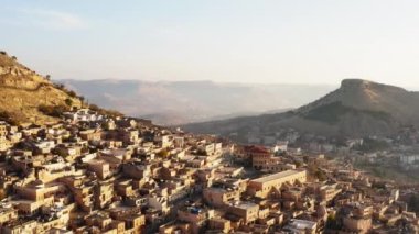 Misopotamya 'daki bir şehir manzarasının insansız hava aracı videosu. Orta Doğu 'da dağları olan bir kayanın üzerinde duran evler ve sokaklar. Mardin 'in havadan görüşü. Yüksek kalite 4k görüntü