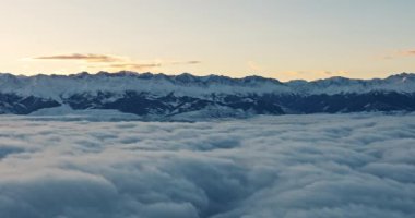 Kış mevsiminde gökyüzünün üstündeki dağ manzarası. Güneşin doğuşunda tepeleri karla kaplı dağlar ya da güzel bir manzarada gün batımı. Bulutların dinlendiği dağlar. Yüksek kalite 4k görüntü