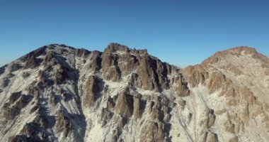 Kayalık dağların güzel doğal manzarası. Kışın karla kaplı kayalık yamaçlar ve kayalık yamaçlarla kaplı bir dağ sırası. İnsanlar olmadan doğanın havadan görünüşü. Yüksek kalite 4k görüntü