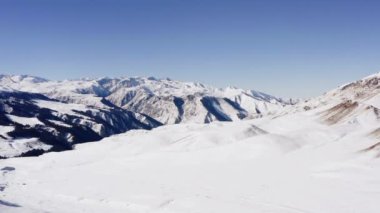 Dağlardaki kış ormanlarının insansız hava aracı videosu. Dağların yamaçlarındaki ağaçlar beyaz karla kaplıdır. Dağ zirveleri ve kayalıklarla dolu güzel bir manzara videosu.. 