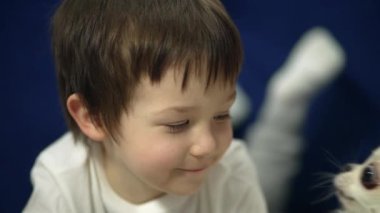 Portrait of a beautiful happy boy who is licked by a dog. Friendship between a child and a pet. The boy smiles when he is kissed by a puppy. High quality 4k footage