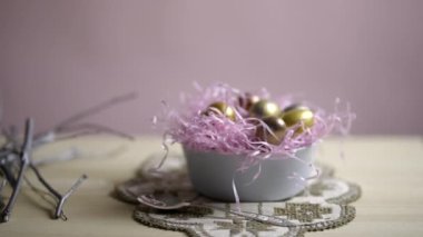 Paskalya yumurtaları ile güzel bir tatil kompozisyonu. Altın ve gümüşle boyanmış süslü bir masada bir tabakta yatıyor. Yüksek kalite 4k görüntü