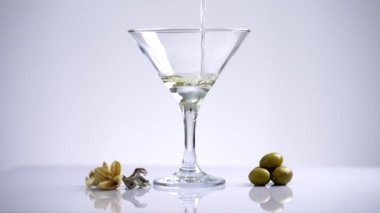 Alkolik bir martini hazırlıyorum. Vermut bardağa doldurulur ve zeytini fırlatılır. Barda ya da restoranda güzel bir alkollü kompozisyonun 4K videosu. Yüksek kalite 4k görüntü