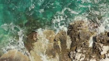 Hava manzaralı mavi okyanus dalgaları kayalık bir kıyıya çarpıyor. Güzel deniz manzarasının arka plan videosu.