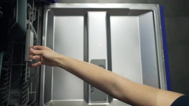 Womens hands open the dishwasher and get clean dishes. The housewife is busy with household chores and washing dishes. Getting a clean plate. High quality 4k footage