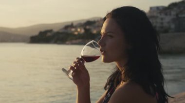 Okyanus kenarında bir bardak şarabı olan bir kız tatilde mutlu olur. Deniz kenarında dik bir tatil, rahatla ve gülümse..