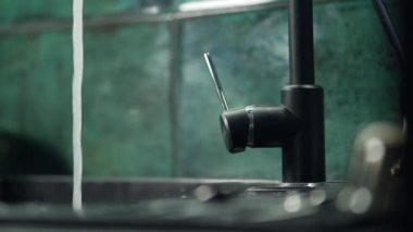 Suyun aktığı mutfak musluğunu kapatıyorum. Mutfak masasındaki lavabodaki suyu eller örtüyor. Yavaş çekim 4K ödev videosu. Yüksek kalite 4k görüntü