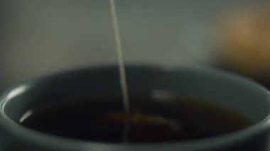 Making tea at home in the kitchen. A womans hand takes a tea bag from a cup and tea flows from it. Slow motion 4K video of cooking hot drink. High quality 4k footage