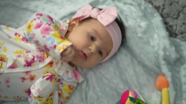 Harika küçük bir bebek yatağa uzanıyor ve kameraya gülümsüyor. Sevimli bebek gülümsüyor ve etrafına bakıyor. Kapatın. Güzel Gülümseyen Bebek. Yüksek kalite 4k görüntü