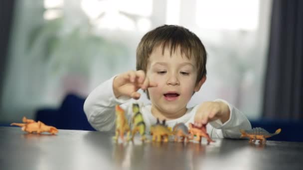 Счастливый Маленький Мальчик Играет Игрушками Детские Руки Двигают Динозавров Стол — стоковое видео