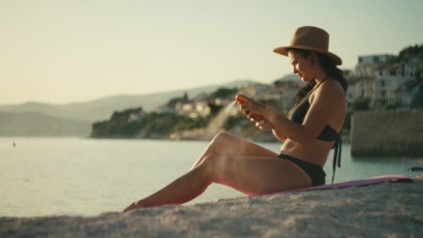 Das Mädchen Sprüht Und Verteilt Sonnencreme Auf Dem Körper Meer — Stockvideo