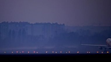Evening airport plane takes off. Illuminated runway on which the plane takes off, and in the background of the city.
