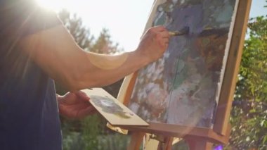 Sanatçı doğada bir resim çizer. Güneşli havada dışarıda hobiler. Tabela üzerinde resim yapmak.