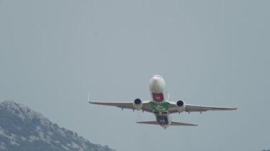 Bir yolcu uçağının dağ manzarasında hareket edişinin yavaş çekim videosu. Uçak gökyüzüne yükseliyor. Yüksek kalite 4k görüntü