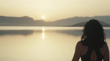 The girl exhales after a morning jog by the sea. Sunrise and tortured sports girl walks by the ocean. High quality 4k footage