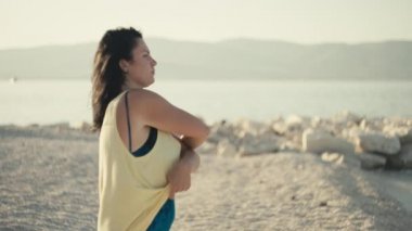 Slow motion video of a girl dropping her T-shirt and running to the sea to swim. Woman on vacation undresses and goes in a swimsuit to the ocean.