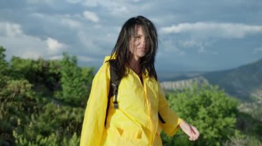 Mutlu ve gülümseyen bir kız dağlarda yürüyüşe çıkar. Güzel bir dağ manzarasında zirvenin fethi sırasındaki turist kadın. Yüksek kalite 4k görüntü