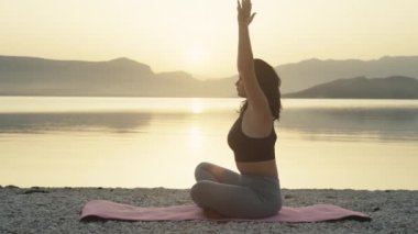 Girl meditates at sunrise by the ocean. Athletic woman doing fitness and yoga in a beautiful landscape. High quality 4k footage