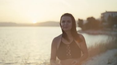 Güneş doğarken deniz kenarında koşan bir kızın yakın çekim videosu. Güzel bir kadın spor ve spor yapıyor ve okyanus kenarında dinleniyor. Yüksek kalite 4k görüntü