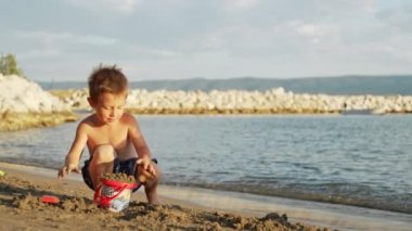 A boy plays in the sand on the beach near the sea. High quality 4k footage