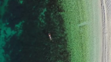 Aerial view of a girl swimming in the ocean. A woman in a swimsuit swims near the beach in the sea. High quality 4k footage