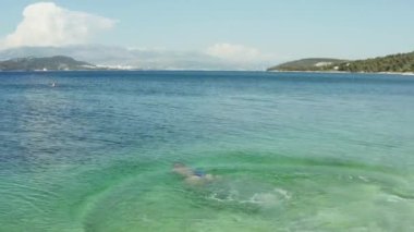 Aerial view of a woman diving into the ocean. The girl on vacation swims in the sea. High quality 4k footage