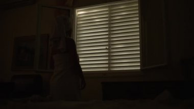 The girl opens the window in the apartment in the morning. A woman wrapped in a towel looks out the window. High quality 4k footage