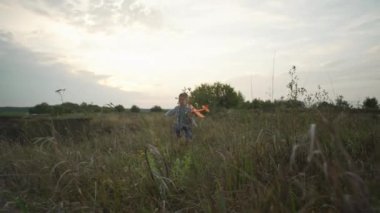 A child is playing and running with an airplane in the park. Happy smiling boy. Active games in nature. Slow motion video. High quality 4k footage