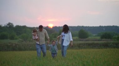 Lifestyle of a happy family walking together holding hands. Happy and smiling children and parents spending time together in the park at sunset. High quality 4k footage