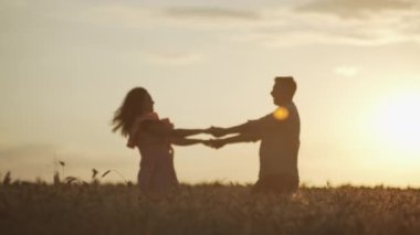 Romantic happy couple dancing together in wheat field. Sunset man and woman holding hands in nature landscape. High quality 4k footage