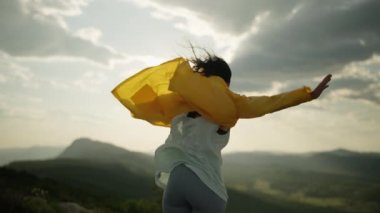 The girl raises her hands to the top of the mountain and feels freedom. A beautiful landscape of mountains at sunset and a woman meditating. High quality 4k footage