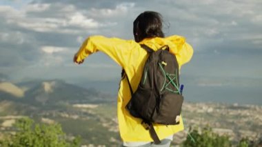 The girl is happy and jumps on top of the mountain. A beautiful woman with a backpack conquered the mountain raises her hands in the mountain after hiking. High quality 4k footage
