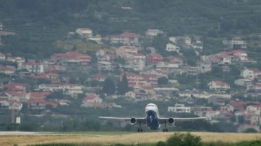Slow motion video of a plane taking off at Split Airport, Croatia. The wheels of the plane come off the runway in the cityscape. High quality 4k footage