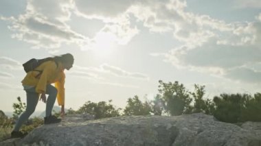 The girl climbs the rocks to the top of the mountain and raises her hands uphill. The feeling of victory and freedom above the clouds in a beautiful mountain landscape. High quality 4k footage