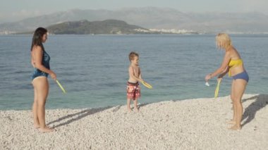 Slow motion video of a family playing tennis and bambinton by the ocean. Beach sports active games, mom and baby playing together. High quality 4k footage