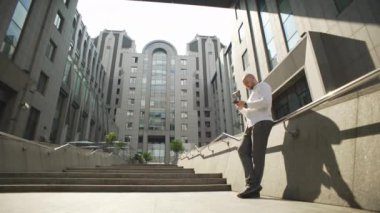 The manager solves business issues by texting on the phone. A serious man writes a message about work near a business center. High quality 4k footage