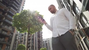 A businessman is texting on the phone near the business center. A serious expression of enthusiasm and concentration, a person conducts negotiations and responds to work emails. High quality 4k 