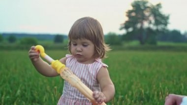 A little girl tries to blow soap bubbles in nature. Slow motion video of a happy child. High quality 4k footage