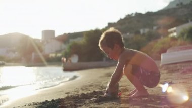 A boy plays with toys on the beach in the sand. A happy child on vacation by the sea in summer is happy. High quality 4k footage