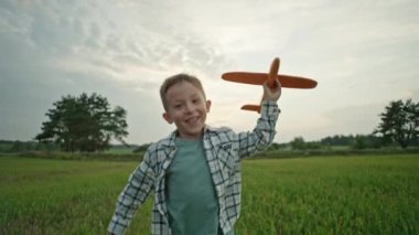 A close-up of a boy who runs with an airplane in his hands and wants to become a pilot. Happy child playing. Kid toys that have fun in nature. High quality 4k footage